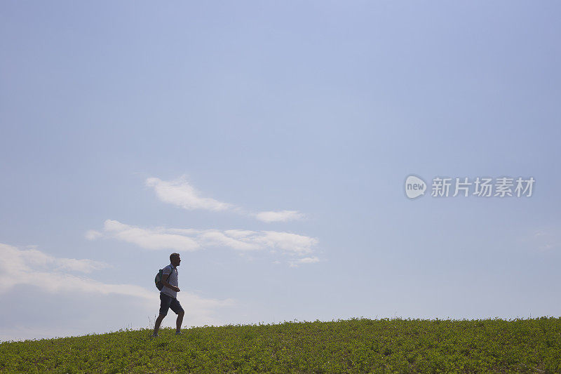 成年徒步旅行者在乡间的自然环境下，越过山的地平线