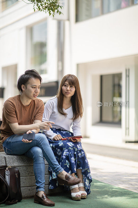 一对年轻夫妇在街上的树下休息