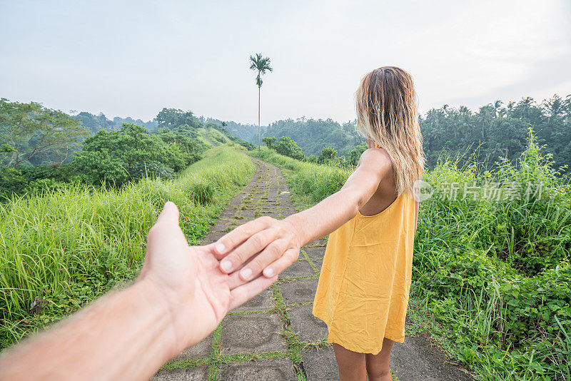 跟随我的概念年轻女子带领男友到稻田在Campuhan岭漫步在巴厘岛，亚洲人旅游奇迹分享爱的概念-