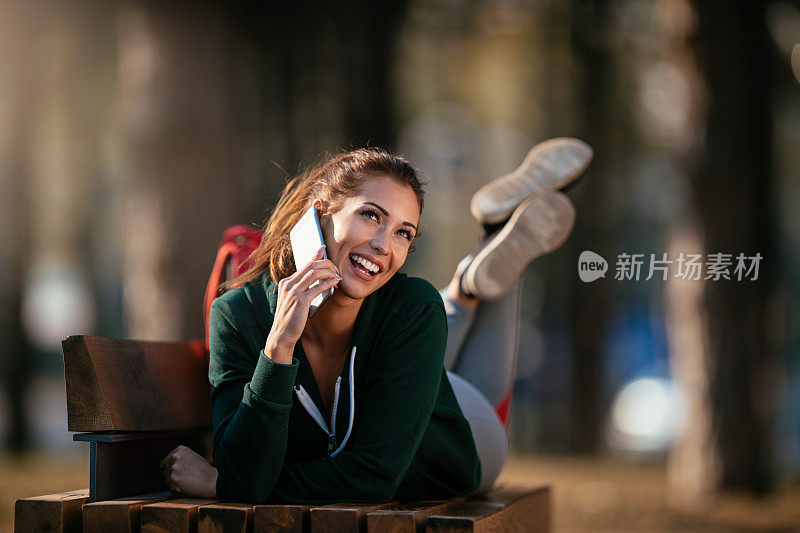 漂亮的年轻运动女性与智能手机在户外