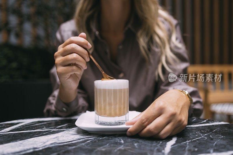 一个无名女子的手在咖啡桌上搅拌一杯咖啡