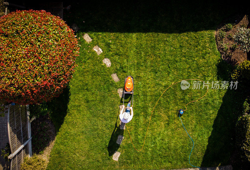 鸟瞰图中的人在花园里用割草机割草