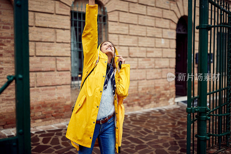 一个年轻的女孩对雨滴落在她身上感到兴奋。走,雨,城市