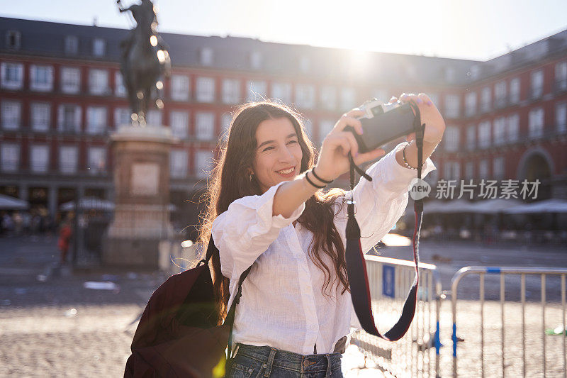 27日，在马德里市长广场的西班牙费利佩三世马术纪念碑前，一名快乐的白人女性正对着镜头微笑自拍