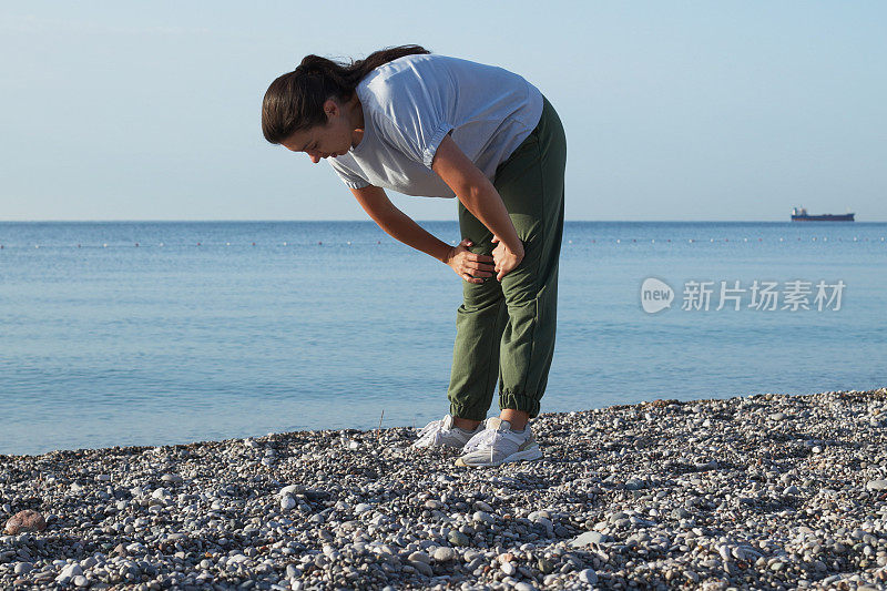 年轻女子早上在海边慢跑后休息，以保持身材