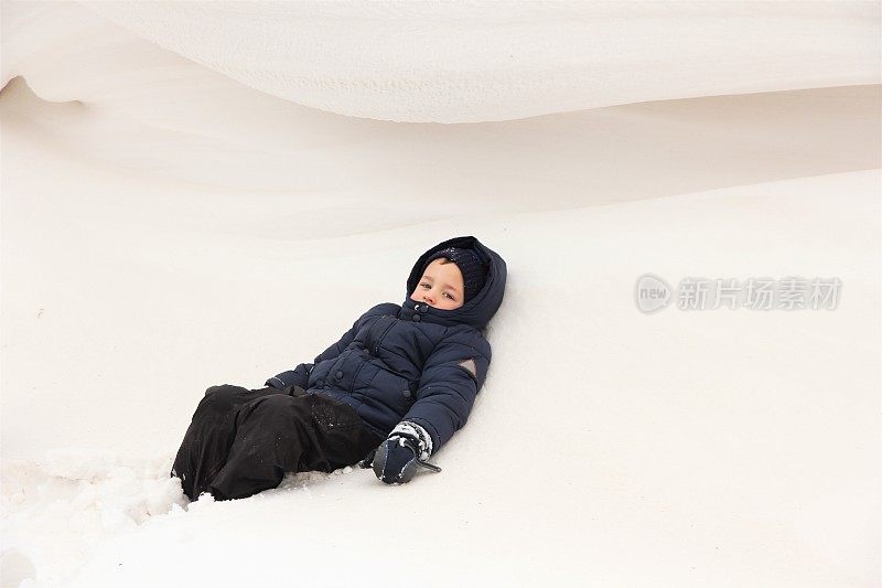 男孩躺在巨大的雕刻雪堆上