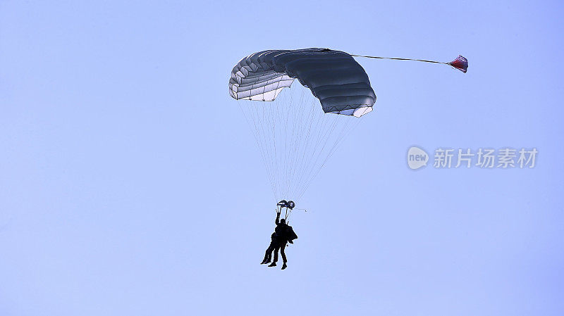 高空跳伞者带着白色伞盖，蓝天白云，特写镜头。