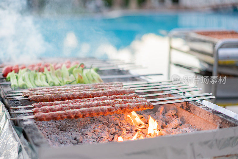 在度假村游泳池附近的火焰上烧烤阿达纳烤肉串