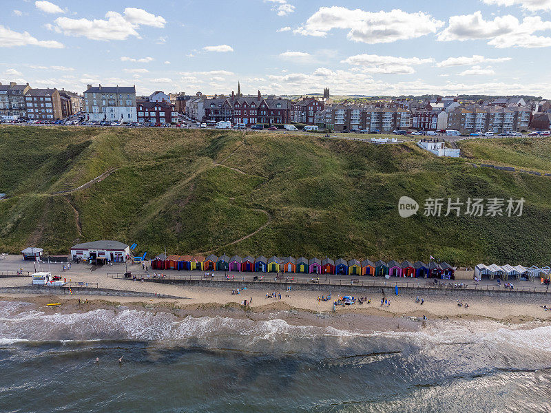 英国北约克郡萨尔特本的空中海岸线场景，冲浪者在平静的北海上。用0级无人机拍摄的