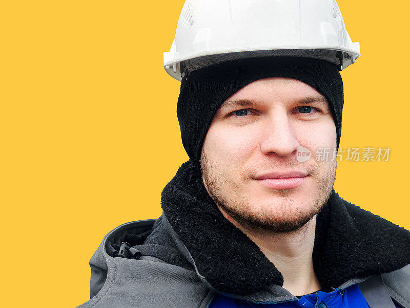 大肖像的人在建筑头盔上的黄色背景。一名中年白人工人自信地直视着镜头。布局与空间复制。