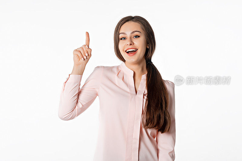 热情的女孩竖起手指，展示logo横幅、产品广告。微笑的年轻女子站在白色的工作室背景