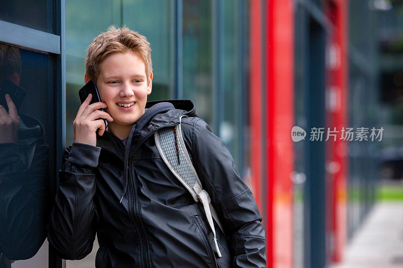 十几岁的男孩微笑着用手机和朋友聊天