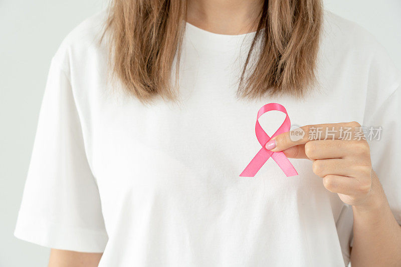妇女手持粉红丝带提高乳腺癌意识。女性健康检查意识。国际妇女节和世界癌症日。象征癌症，象征保健，支持患者，及时诊断