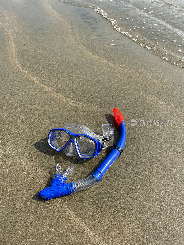 水肺面罩和浮潜的特写图片，在退潮时留在沙滩上，海浪在海岸上破碎，高架视图，复制空间