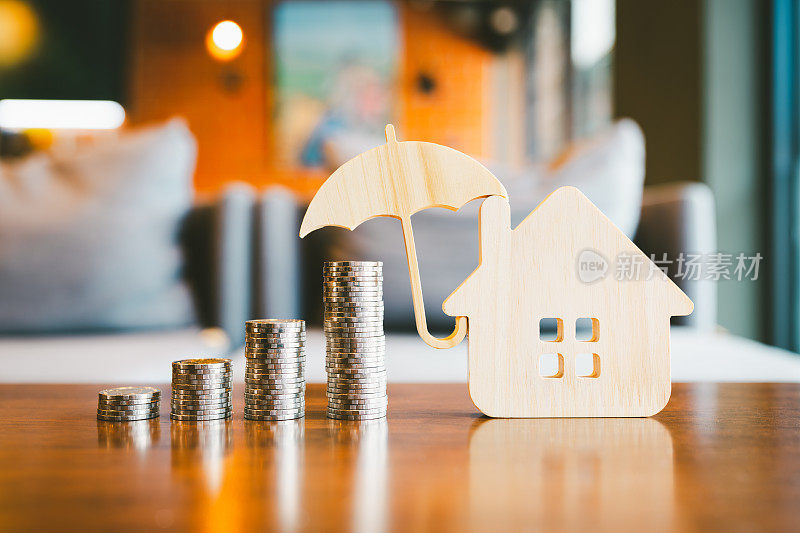 模型伞用房子和木桌上的硬币概念的保险制度，节省了健康保险的费用