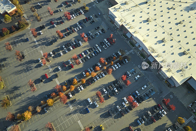 俯视图，许多汽车停在停车场前的条形购物中心广场。消费主义与市场经济的概念