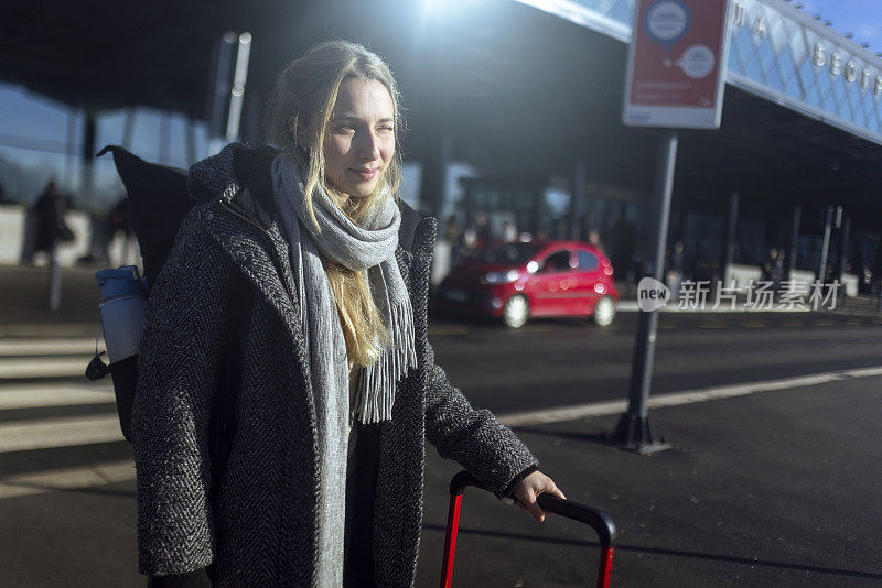 一位女士刚在机场降落，她拖着一个手提箱离开了机场
