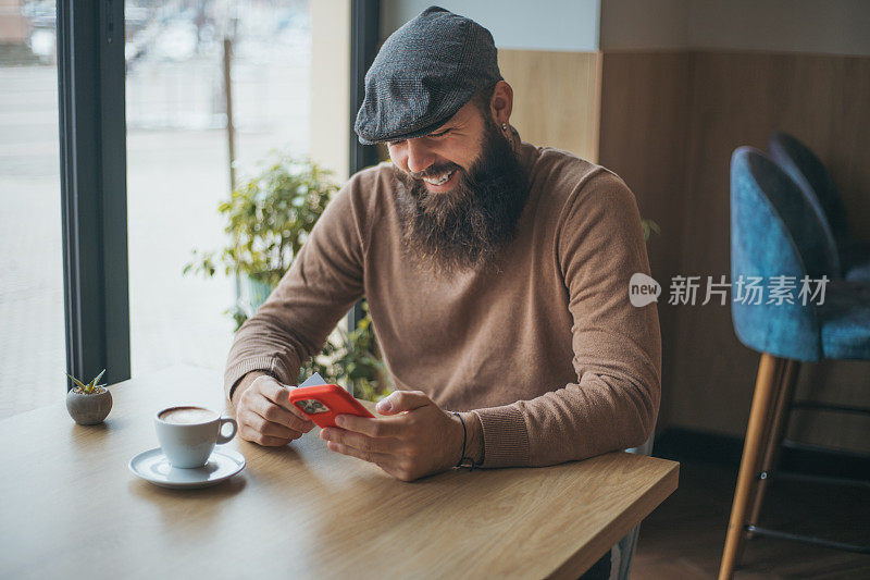 在咖啡馆使用智能手机的快乐男人的肖像