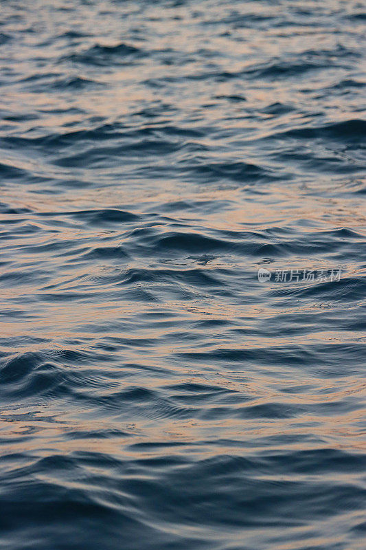 海水表面水平的全帧图像，阳光在波涛汹涌的水面上闪闪发光，波浪背景