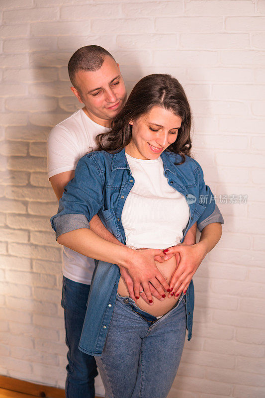 年轻的孕妇和丈夫在她的肚子上做了一个心形