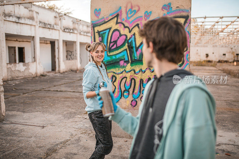 两位才华横溢的艺术家在一座废弃建筑的墙上画上五颜六色的涂鸦，共同创作了一件艺术品