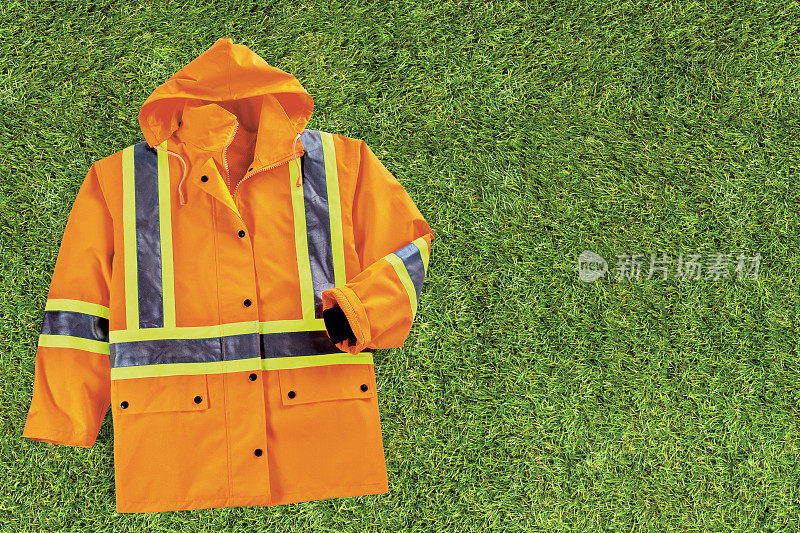 安全橙色工作服，在草地上有黄色和黑色反光带