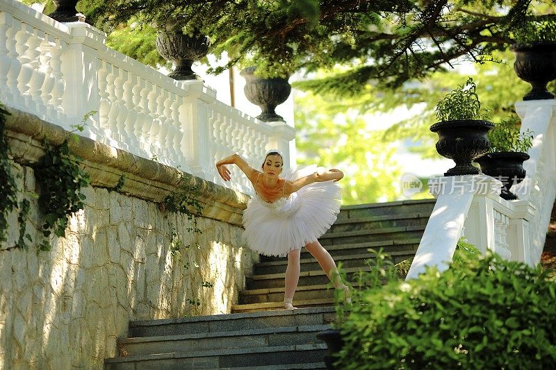 美丽的芭蕾舞演员在公园的楼梯上跳舞