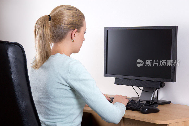 后视图的女人与个人电脑在办公室