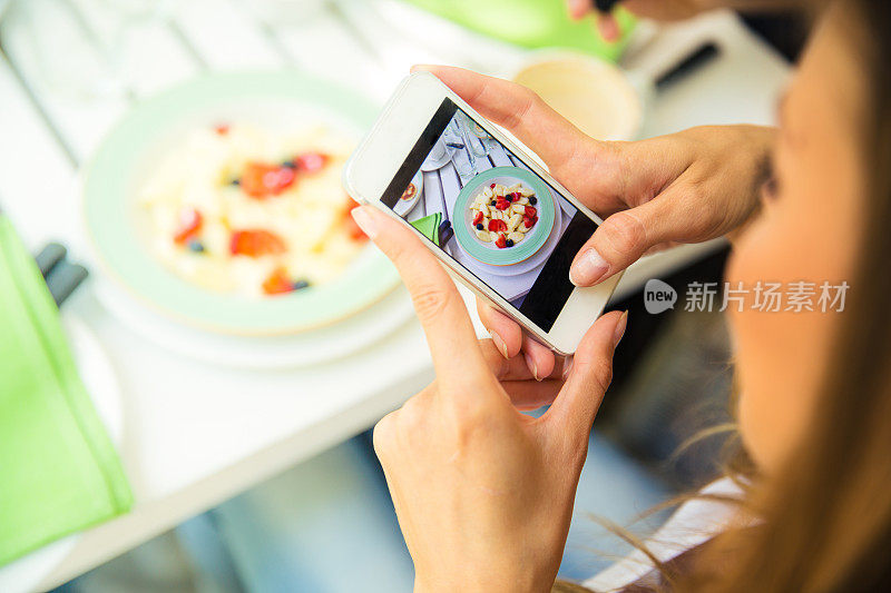 一个女人在用智能手机拍食物
