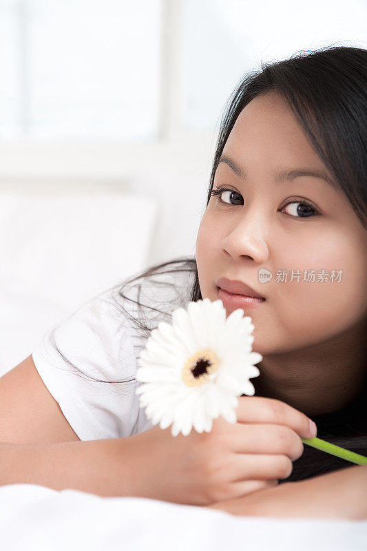 亚洲女性抱着非洲菊在床上