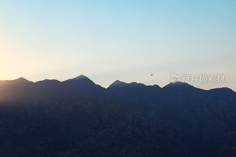 一架小飞机在夕阳下飞过山脉