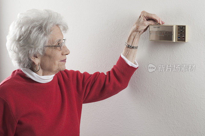 老妇人在调节家里的恒温器