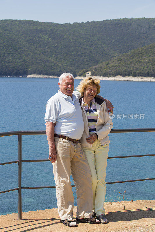 老年情侣微笑着站在沙滩上度假