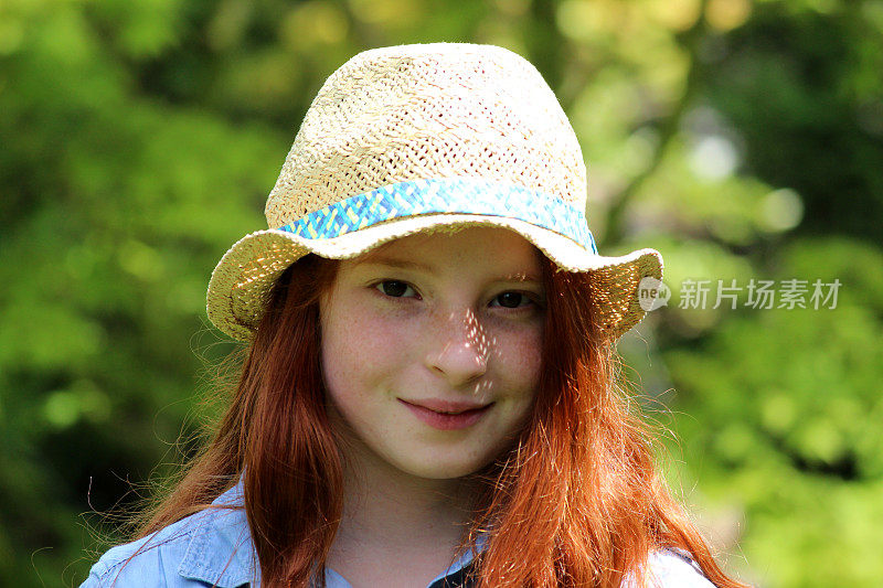 美丽的年轻快乐的女孩在花园阳光戴着草帽