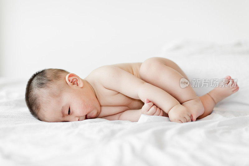 赤裸的可爱小男孩睡在白色的床上