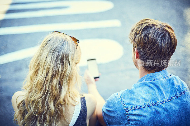 后视图的男人拿着智能手机的女人