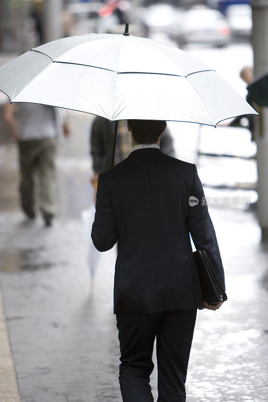 行政人员在雨中走在城市街道上