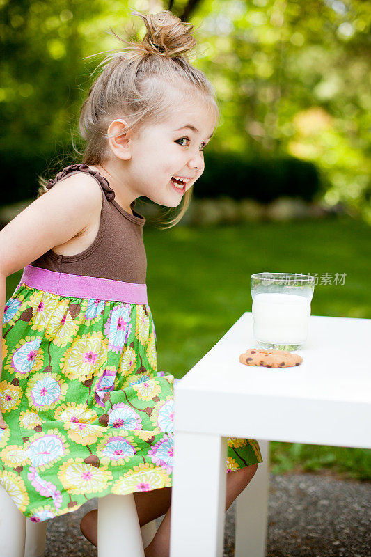 可爱的女孩为她的饼干和牛奶感到兴奋!