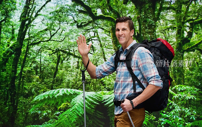 微笑的男性徒步旅行者在雨林和挥手