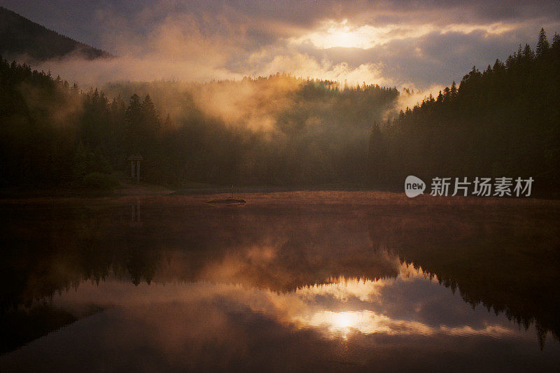 日落时山上的湖上有雾。