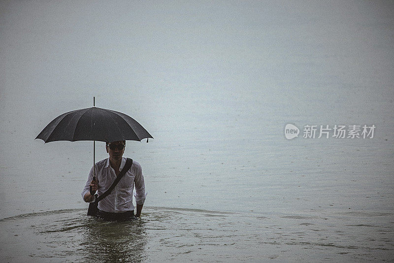 帅气的男人穿着白衬衫，在下雨的时候撑着伞