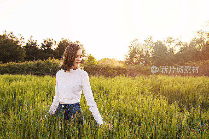 一个年轻的女人在麦田里感觉自由自在