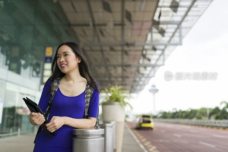 迷人的长发亚洲女人在机场候机厅外等候