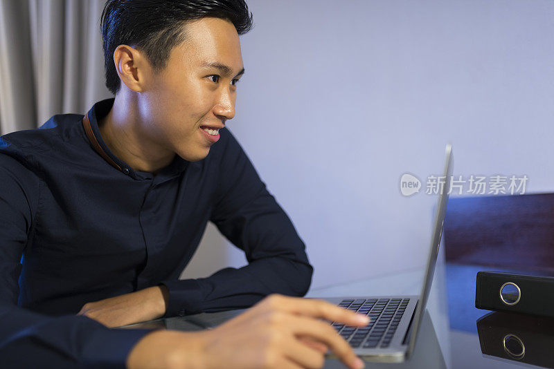 年轻的亚洲商人用笔记本电脑远程办公