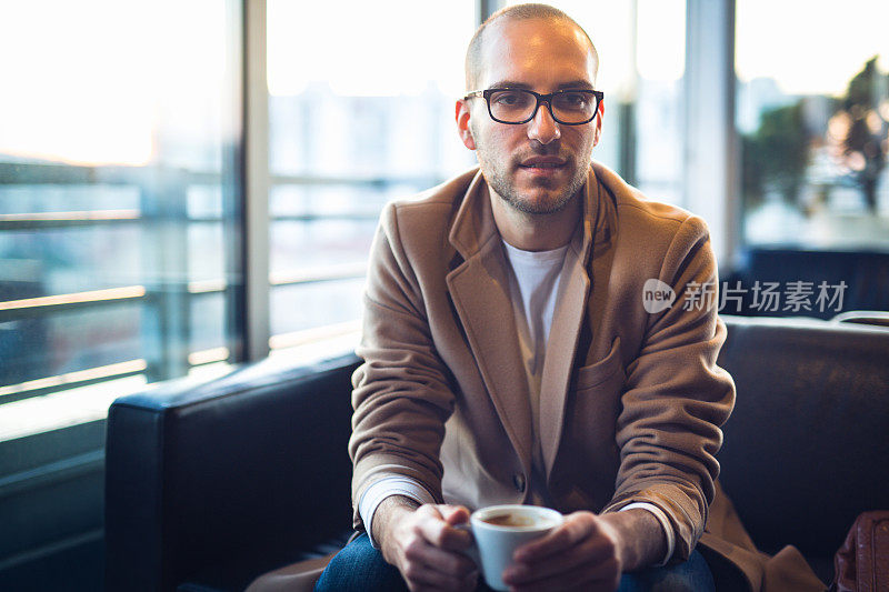 在咖啡店拿着咖啡杯的年轻人