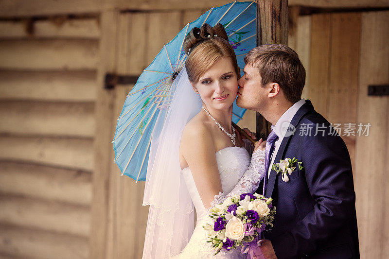 新郎在伞下亲吻新娘的脸颊