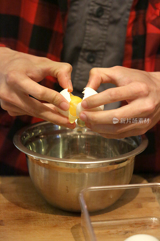 一个年轻人在他的厨房里用搅拌碗打鸡蛋