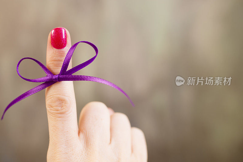 紫色的社会意识丝带系在食指上。提醒。