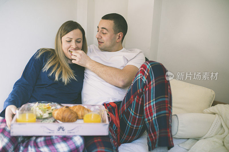 年轻夫妇在床上吃早餐