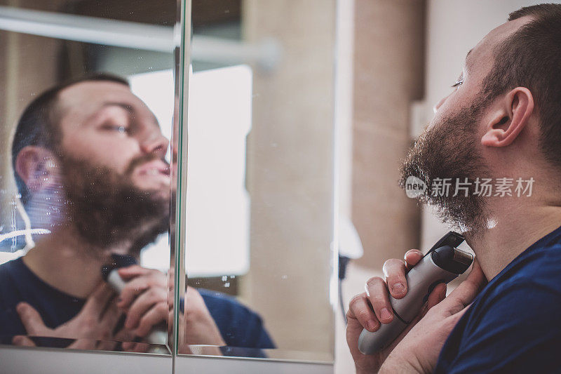 男人在浴室里用电动剃须刀刮胡子